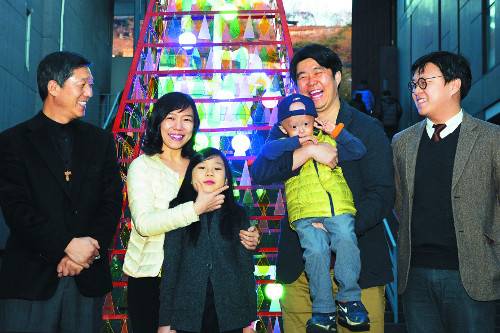 국내 유일의 소아 조로증 환자인 홍원기군(오른쪽 세 번째)과 가족들이 10일 서울 종로구 동숭교회 마당에 세워진 ‘워터풀 크리스마스트리’ 앞에서 이 교회 서정오 담임목사(왼쪽 첫 번째)와 함께 활짝 웃고 있다. 김보연 인턴기자