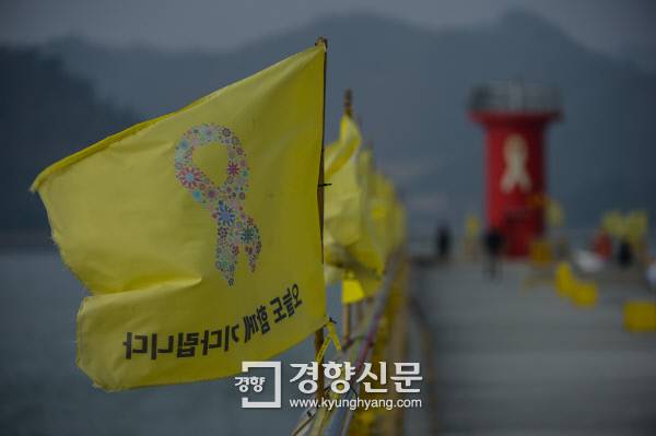팽목항 등대로 가는 길 난간에 ‘오늘도 함께 기다립니다’라고 적힌 노란 깃발들이 바람에 날리고 있다.  이준헌 기자 ifwedont@kyunghyang.com
