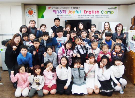 시원공익재단의 제18회 Joyful English Camp 발대식에 참석한 내빈과 강사들 그리고 아이들이 함께 포즈를 취하고 있다.