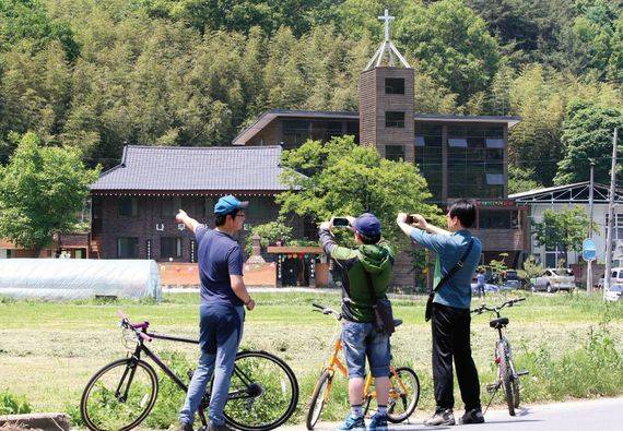 대구시 달성군 가창면 삼산리 농촌마을을 지나는 시민들이 나란히 자리 잡은 절과 교회의 모습이 신기한 듯 휴대폰을 이용해 사진을 찍고있다. 양측은 “다른 종교이지만 서로 존중하며 이웃처럼 지내고 있다”고 밝혔다. [중앙포토]