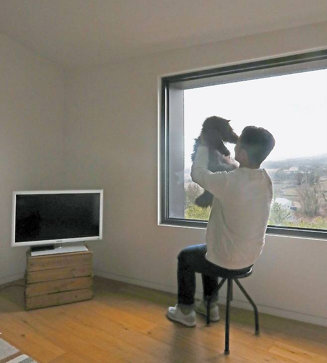 헤어 스타일리스트 김정한씨가 제주 애월집에서 반려묘 로니와 즐거운 한때를 보내고 있다. 2015년 제주에 이사오면서 가구를 최소화했다. TV받침대는 귤 상자를 겹쳐 만들었고 수납공간도 가급적 두지 않았다.