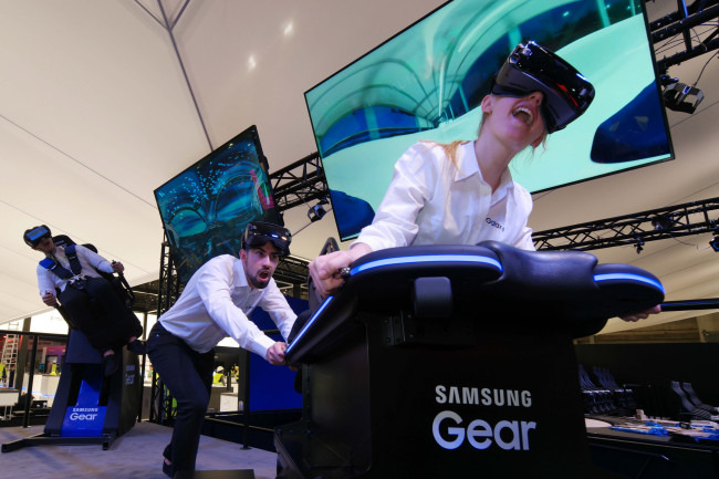 Models experience virtual reality through Samsung Electronics’ Gear VR at the VR 4D Experiential Zone at the company’s booth for the Mobile World Congress 2017 in Barcelona on Sunday. (Samsung Electronics)