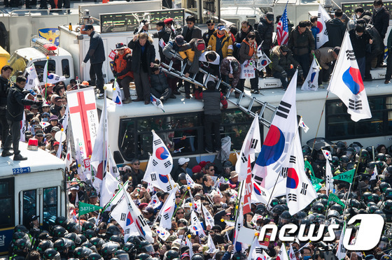 10일 서울 종로구 안국역사거리에서 열린 대통령탄핵기각을위한국민총궐기운동본부(탄기국) 주최 태극기집회에 참석한 시민들이 박근혜 전 대통령의 탄핵이 인용되자 경찰 차벽을 넘어 헌법재판소 진입을 시도하고 있다.2017.3.10/뉴스1 © News1 유승관 기자