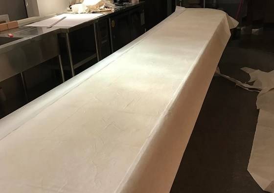 바 형태의 식탁에 한지를 겹겹이 바르는 작업을 할 때 모습. 온풍기를 가동하며 풀을 발라 한지를 붙였다.