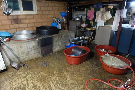 주력상품인 두부 만드는 부엌에는 어른이 들어가 앉아도 남을 만큼 큰 가마솥이 있다. 매일 두부를 쑨다. 저녁에 만든 두부 간수를 빼려고 고무 함지박에 담아 두고 물을 흘려 보내고 있다.