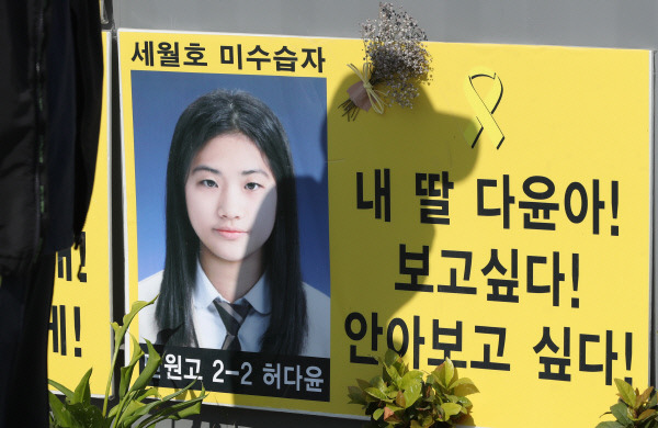 세월호 참사 발생 1천129일 만에 미수습자인 단원고 학생 허다윤 양의 신원이 확인된 19일 오후 전남 목포신항 ‘미수습자 가족 만남의 장소’ 앞 허 양의 사진 위로 아버지 허흥환 씨의 그림자가 드리워져 있다. 세월호 현장수습본부는 지난 16일 세월호 3층 객실 중앙부 우현에서 수습된 유골의 치아와 치열을 감정한 결과 단원고 허다윤 양으로 확인됐다고 이날 밝혔다. 연합뉴스