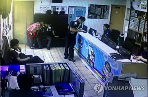 (부산=연합뉴스) 지난 27일 오후 보이스피싱 조직원의 전화를 받은 이모(68·여) 씨가 부산 영도경찰서 대교파출소를 찾아와 한 경찰관에게 귓속말로 피해 신고를 하는 모습. 이 씨의 오른손에는 범인과 통화 중인 휴대전화기가 들려 있다. 2017.6.28 [부산 영도경찰서 제공 영상 캡처=연합뉴스]      youngkyu@yna.co.kr