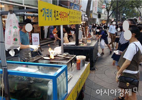 11일 저녁 명동 가리비치즈버터구이 노점 앞에 외국인 관광객들이 서 있다.(사진=오종탁 기자)