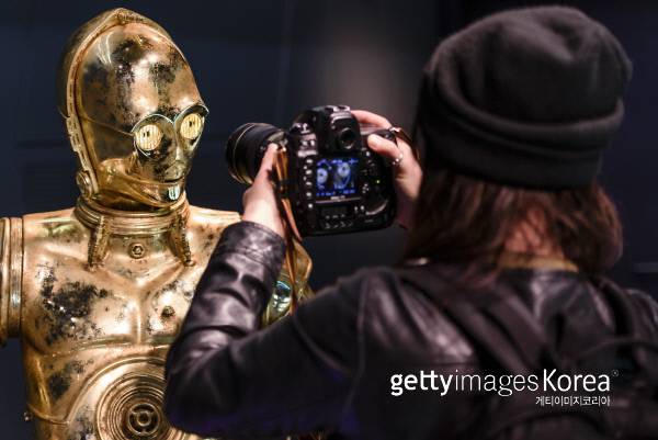 독일 베를린에서 지난해 5월 8일 열린 스타워즈 피규어 전시회에 참석한 한 기자가 스타워즈의 로봇 ‘C-3PO’의 피규어를 카메라로 찍고 있다. Photo by Clemens Bilan/Getty Images