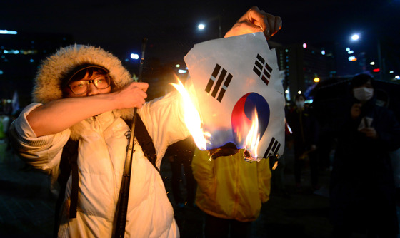 세월호 참사 1주년 추모집회 참가자가 4월 18일 오후 서울 광화문 앞에서 경찰과 대치하는 도중 태극기를 불태우고 있다. /사진=뉴스1