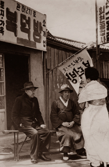 1960년대 말 서울 회현동의 복덕방 앞에서 한 중년 여성이 부동산 중개업자와 얘기하고 있다.  경향신문 자료사진