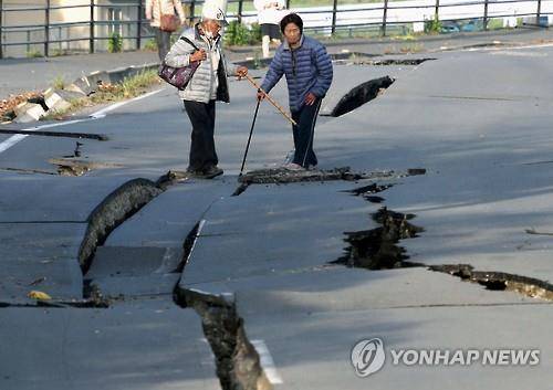 (구마모토 교도/AP=연합뉴스) 16일 일본 구마모토현 마시키마치에서 주민들이 지진으로 갈라진 도로에 서 있다.