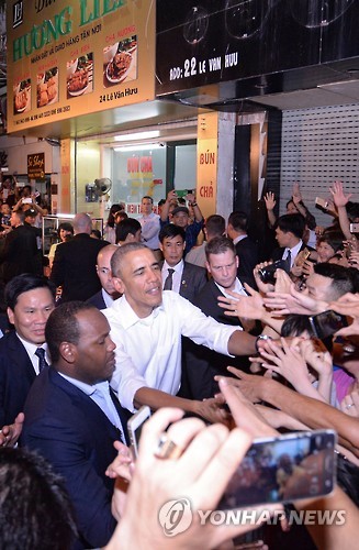 (EPA=연합뉴스) 베트남 하노이 쌀국수 식당에서 저녁먹은 후 환호하는 베트남인들에게 인사하는 오바마 대통령