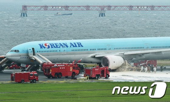 27일 오후 일본 도쿄 하네다(羽田) 국제공항에서 김포공항을 향해 떠나려던 대한항공 2708편(보잉777) 여객기에서 화재로 추정되는 연기가 발생했다. 기내에 탑승한 승객과 승무원은 비상 슬라이드를 이용해 모두 대피했다. 소방관들이 연기가 피어오른 왼쪽 엔진 부분에 소화액을 뿌리고 있다.© AFP=뉴스1 © News1 최종일 기자