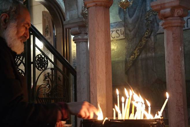 성묘교회에서 수도자가 불 붙인 초를 꽂으며 기도하고 있다. 기도는 자신을 태우며 불을 밝히는 초를 닮은 걸까.