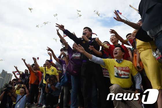 필리핀과 베트남 시민운동가들이 12일(현지시간) 마닐라에서 헤이그 상설중재재판소의 판결을 기다리며 염원을 담은 꽃을 날리고 있다.   © AFP=뉴스1