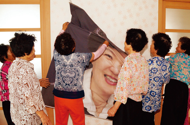 경북 성주군 한 노인정에서 노인들이 한쪽 벽에 커다랗게 붙어 있던 박근혜 대통령 사진을 떼고 있다. [뉴시스]