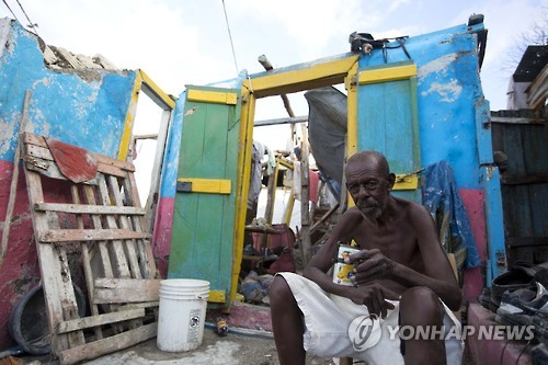 7일(현지시간) 아이티 북서부 '그라당스'의 중심도시 제레미에서 한 주민이 허리케인 매슈에 무너진 집 앞에 망연자실한 표정으로 앉아있다. [AP=연합뉴스]