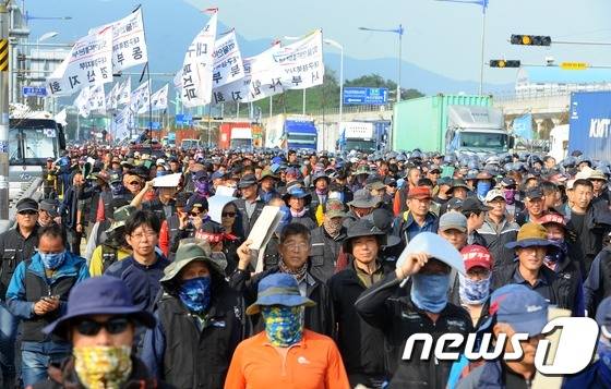 화물연대 총파업 사흘째인 12일 오후 부산국제신항국제터미널 앞 거리행진하는 노조원들 뒤로 정상운행 하는 화물차가 지나가고 있다. 2016.10.12/뉴스1 © News1 여주연 기자