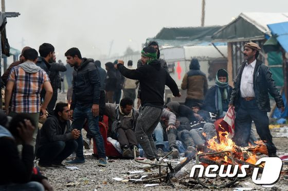 24일(현지시간) 프랑스 칼레의 철거가 진행 중인 정글 난민캠프의 모닥불 주위에 난민들이 모여있다.© AFP=뉴스1 © News1 우동명 기자