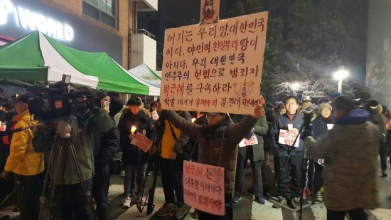 26일 강원도 춘천 김진태 의원 사무실 앞에서 열린 촛불집회에서 한 시민이 박근혜 대통령의 구속과 김 의원의 사퇴를 촉구하는 플랜카드를 들고 있다.