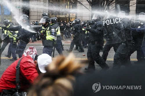 도널드 트럼프 미국 대통령의 취임식이 열린 20일(현지시간) 워싱턴DC에서 경찰이 반(反)트럼프 시위대에 취루액을 뿌리고 있는 모습 [AP=연합뉴스]