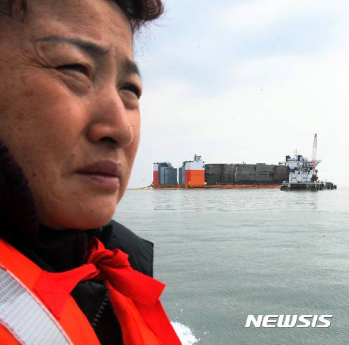 【진도=뉴시스】신대희 기자 = 26일 오전 전남 진도군 맹골수도에서 중국 인양업체 상하이샐비지가 반잠수식 선박에 부양된 세월호 선체의 배수 작업을 벌이고 있다. 미수습자 단원고 양승진 교사의 아내 양백형씨가 세월호를 바라보고 있다. 세월호는 25일 오후 9시15분께 선체 전체가 해수면 위로 올랐다. 2017.03.26. sdhdream@newsis.com