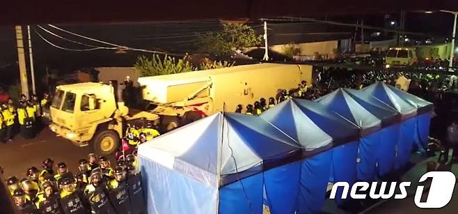 26일 새벽 경북 성주골프장으로 사드(THAAD·고고도미사일방어체계) 장비가 경찰 통제 속에 들어가고 있다. 골프장 입구에서는 이에 반대하는 주민들과 경찰이 대치하고 있다.(페이스북) 2017.4.26/뉴스1