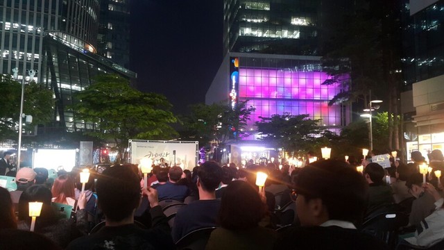 28일 서울 상암동 ‘씨제이 이앤엠’(CJ E&M) 사옥 맞은편에서 열린 시민추모문화제에 모인 시민들이 촛불을 들어보이고 있다.