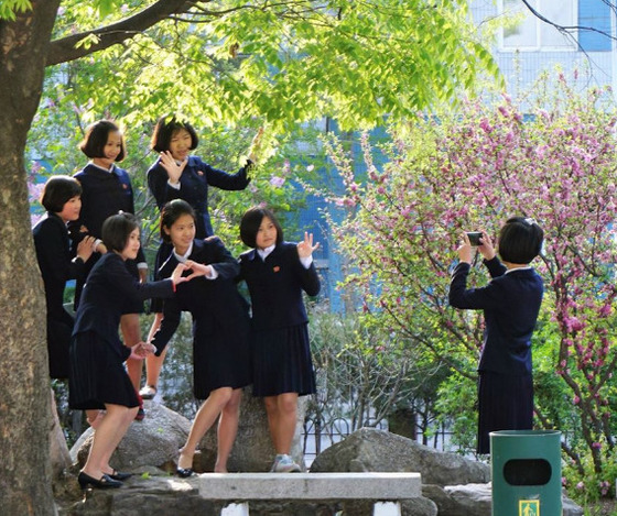 평양 대동문 인근에서 핸드폰 사진을 찍고 있는 북한 여고생들. 손으로 하트모양을 만든 친구들을 핸드폰으로 찍는 학생의 모습이 진지해보인다.[Sejin Pak 페이스북]