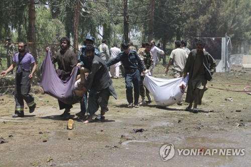 22일 아프가니스탄 헬만드 주 주도 라슈카르가에서 시민들이 테러 희생자들의 시신을 옮기고 있다.[AP=연합뉴스]