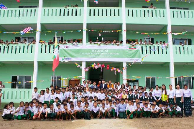 현대건설은 지난 23일(현지시간) 미얀마 딸린타운십 상아티마을에서 현대건설 관계자, 정부 관리자, 학교 교장 및 교직원, 학생 등 800여명이 참석한 가운데 초등학교 완공식을 가진 후 기념촬영하고 있다. 현대건설 제공