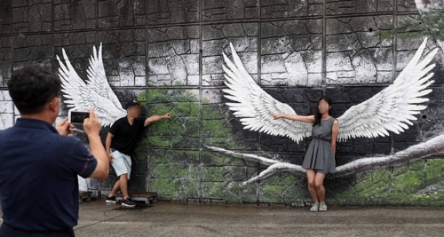 (통영=연합뉴스) 김동민 기자 = 20대 커플이 동피랑 마을 천사 날개에서 사진을 찍고 있다.
