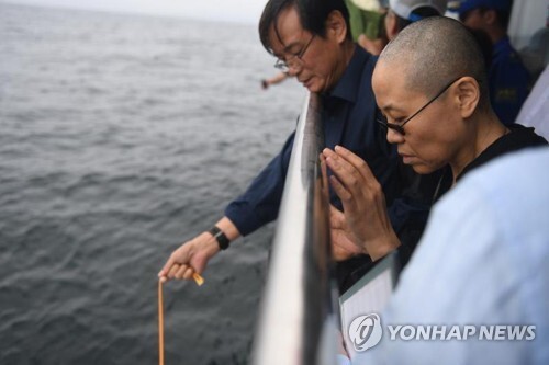 지난 15일 노벨평화상 수상자인 중국 인권운동가 류샤오보의 시신이 화장된 뒤 랴오닝성 다롄 앞 바다에 해장(海葬)됐다. 류샤오보 동생 류샤오쉬안(오른쪽 2번째)이 유골함을 바다에 내리는 모습을 아내 류샤가 바라보고 있다.