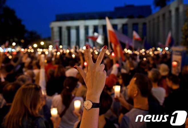 지난 23일(현지시간) 폴란드의 수도 바르샤바에서 시민들이 촛불과 국기를 들고 반정부 시위를 하고 있다. © AFP=뉴스1