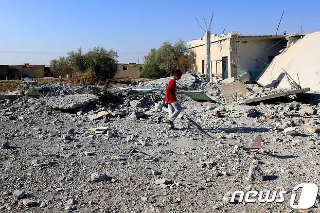 14일(현지시간) 시리아 라카 서부에서 한 소년이 공습으로 파괴된 건물 잔해 위를 있다. © AFP=뉴스1