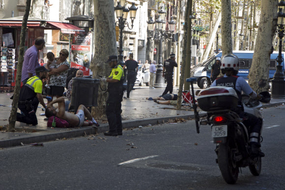 인도에 쓰러진 사람들  - 17일(현지시간) 스페인 바르셀로나 람블라스 거리 보도로 돌진한 차량 테러로 부상을 당한 시민을 경찰이 돌보고 있다.EPA 연합뉴스