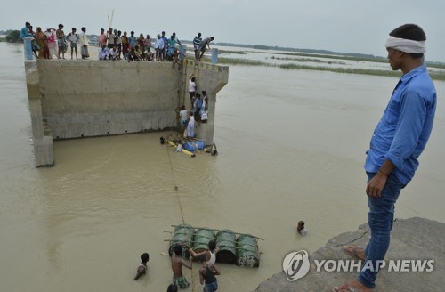 18일 인도 동부 비하르 주 푸르니아 지역에서 홍수에 다리가 끊기자 주민들이 임시로 뗏목을 만들어 물을 건너려고 하고 있다.[AFP=연합뉴스 자료사진]