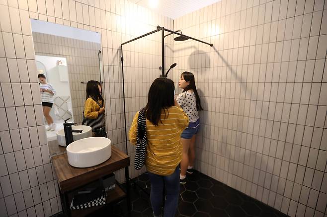 관람하던 학생들이 샤워기 밑에서 사진을 찍고 있다. 신인섭 기자