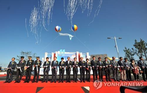 (속초=연합뉴스) 21일 오후 속초항에서 열린 속초항국제크루즈터미널 준공식에 참석한 해양수산부와 강원도, 속초시 관계자를 비롯한 초청인사들이 축하테이프를 자르고 있다. 속초항 크루즈시대를 연 국제크루즈터미널은 국비 373억원을 투입해 지상 3층으로 지어졌다.  [속초시청 제공=연합뉴스]     momo@yna.co.kr