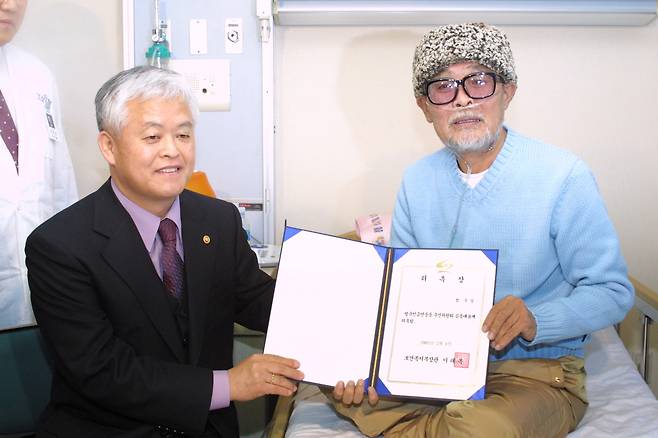 2002년 2월 이태복 당시 보건복지부 장관이 국립암센터에 입원중인 코미디언 이주일 씨에게 범국민금연운동추진위원회 공동대표 위촉장을 전달하고 있다. 이씨는 그해 금연 광고에 출연한 뒤 폐암이 악화돼 숨졌다. [중앙포토]