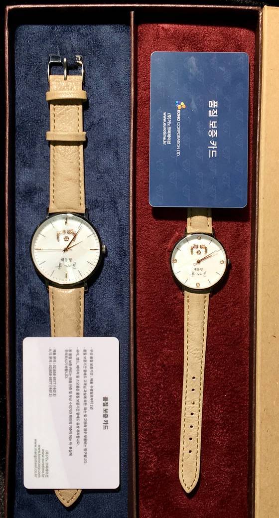 문재인 대통령 이름이 새겨진 기념품용 손목시계 남성용과 여성용. 시계 앞면에는 봉황 마크와 ‘대통령 문재인’이라고 쓰여 있고, 뒷면에는 ‘사람이 먼저다’란 글귀가 쓰여 있다. [연합뉴스]