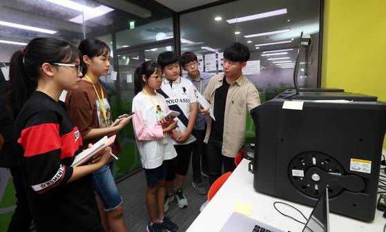 중학생들이 3D 프린터가 물체를 제작하는 과정을 바라보고 있다. 원동현(오른쪽, 기계공학과 13학번)씨는 "3D 프린터 작동 원리를 인쇄물 출력과정과 비슷하다"고 설명했다. 강정현 기자