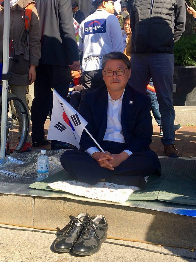 박근혜 전 대통령 석방을 촉구하며 단식 12일째를 맞은 대한애국당 조원진 의원이 21일 서울 대학로 마로니에 공원에서 열린 ‘박근혜 정치투쟁선언 지지 집회’에 참석해 눈을 감은 채 태극기를 들고 있다. 최민영 기자 mymy@hani.co.kr