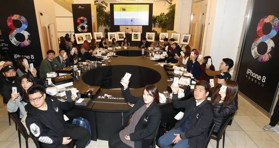 3일 오전 서울 중구 루프트커피에서 열린 SK텔레콤의 아이폰8 국내 출시 개통 행사에 초청받은 40여 명의 고객이 숫자 '8'을 형성화한 테이블에 둘러앉아 아이폰8을 들고 포즈를 취하고 있다.[연합뉴스]
