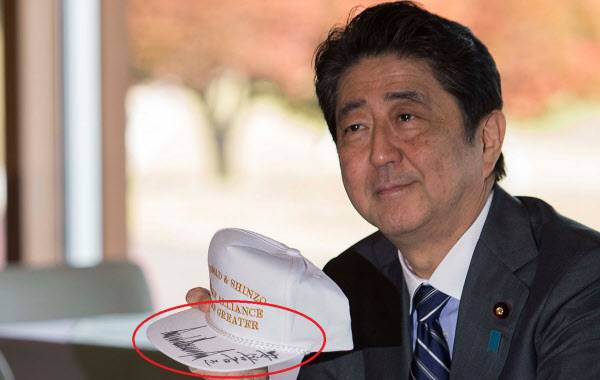 아베 신조 일본 총리의 서명이 오른쪽 구석에 치우쳐져 있는 모습. 그에 반해 트럼프 대통령의 서명은 모자챙 가운데에 크게 자리잡고 있다./AFP=연합뉴스