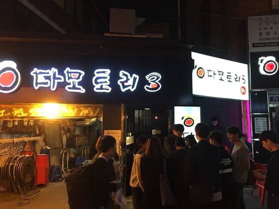 신촌의 감성주점 입구에서 손님들의 나이(1990년 이전 출생)를 확인하는 모습. [여성국·하준호 기자]