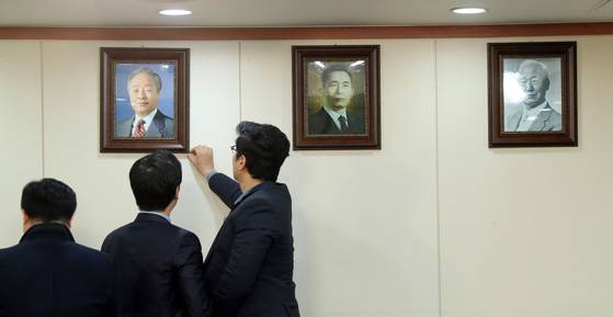 자유한국당 당직자들이 17일 오전 서울 여의도 당사 회의실 벽에 걸린 김영삼 전 대통령의 사진을 바로잡고 있다. 박종근 기자
