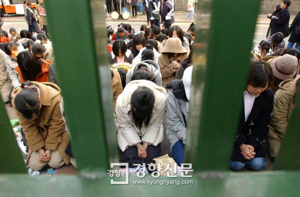 2002년 11월 6일 수능고사장인 서울 이화여고 교문 밖에서 응원나온 후배 학생들이 시험이 시작되기 직전 꿇어앉은 채 3학년 선배들이 좋은 성적을 올리도록 기도하고 있다. 박민규 기자