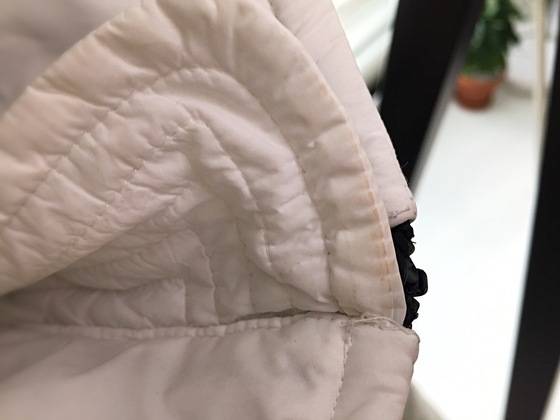 흰색 패딩의 목 부분에 노란색 화장품이 묻어 있다.